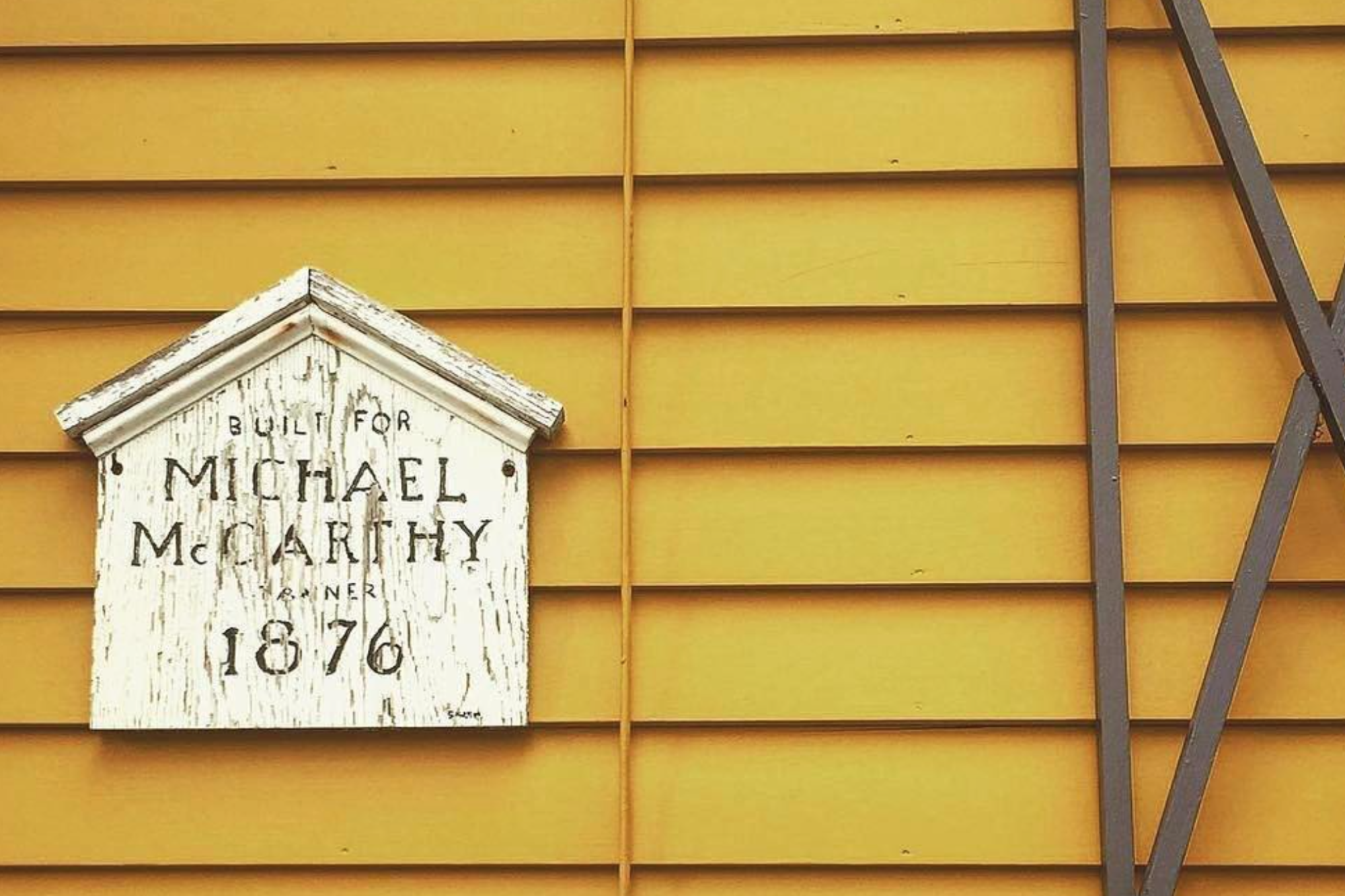 House history plaque on a yellow building