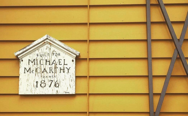 House history plaque on a yellow building