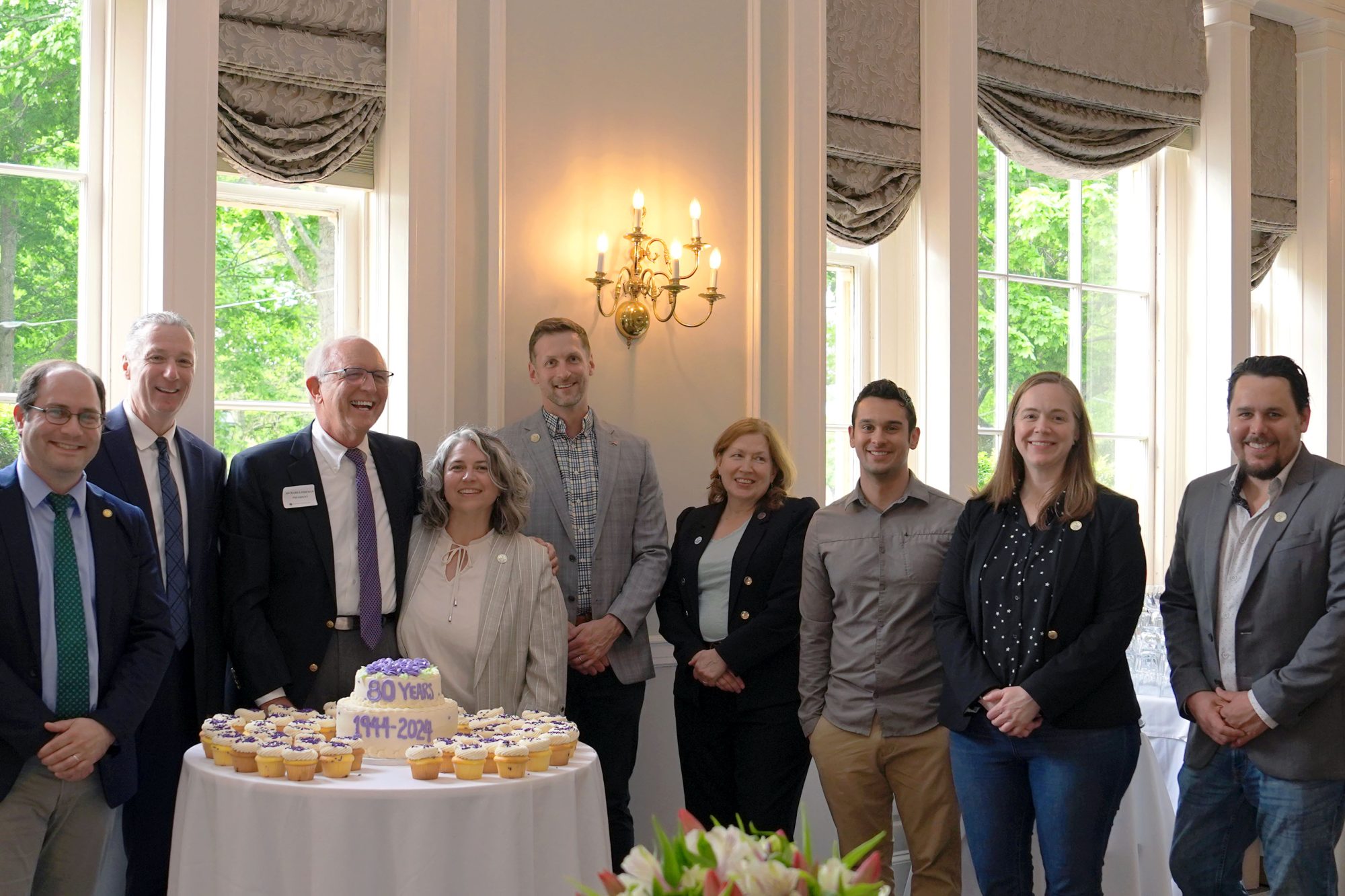 People stand next to a birthday cake