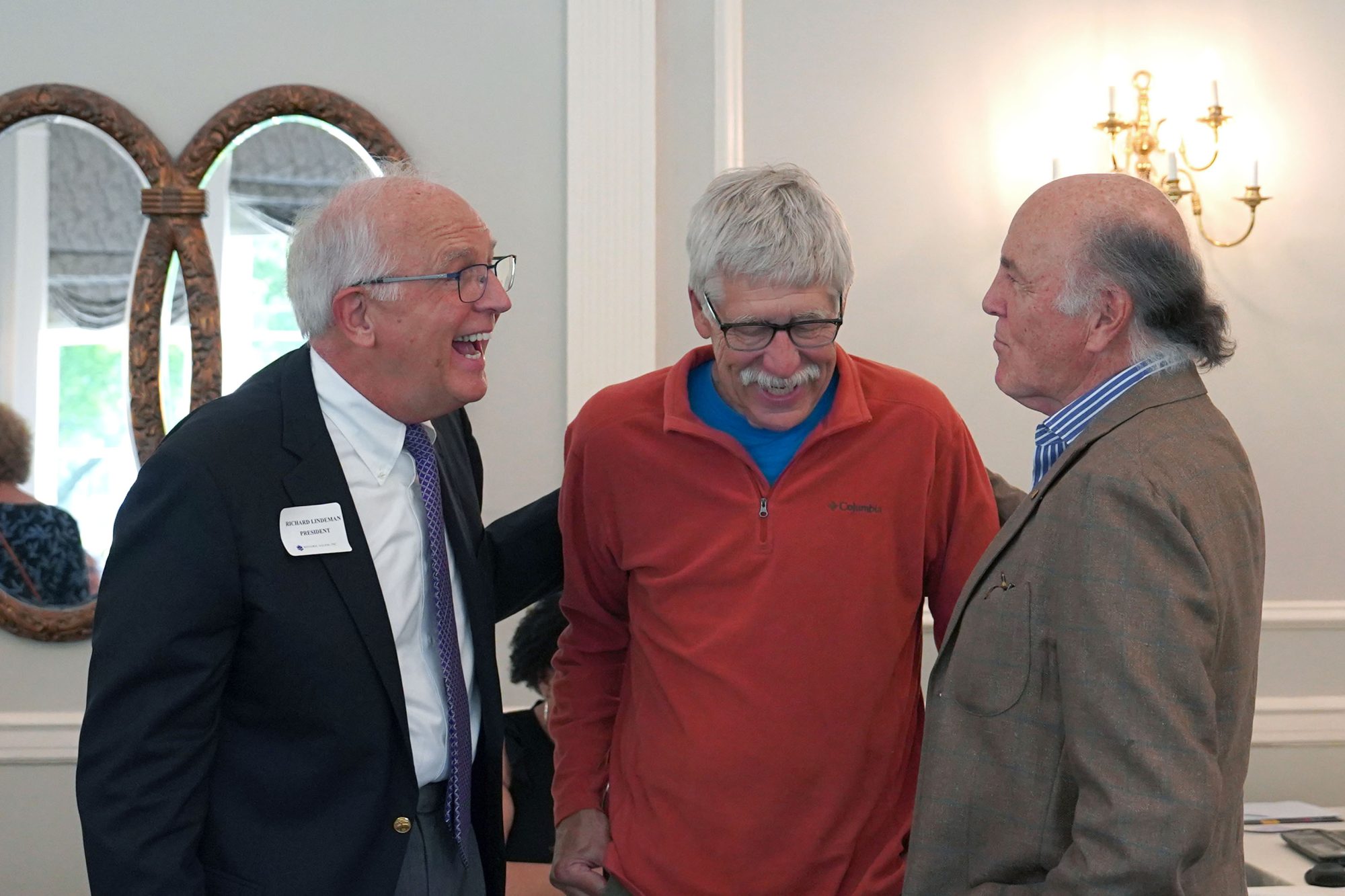 Three men stand together laughing
