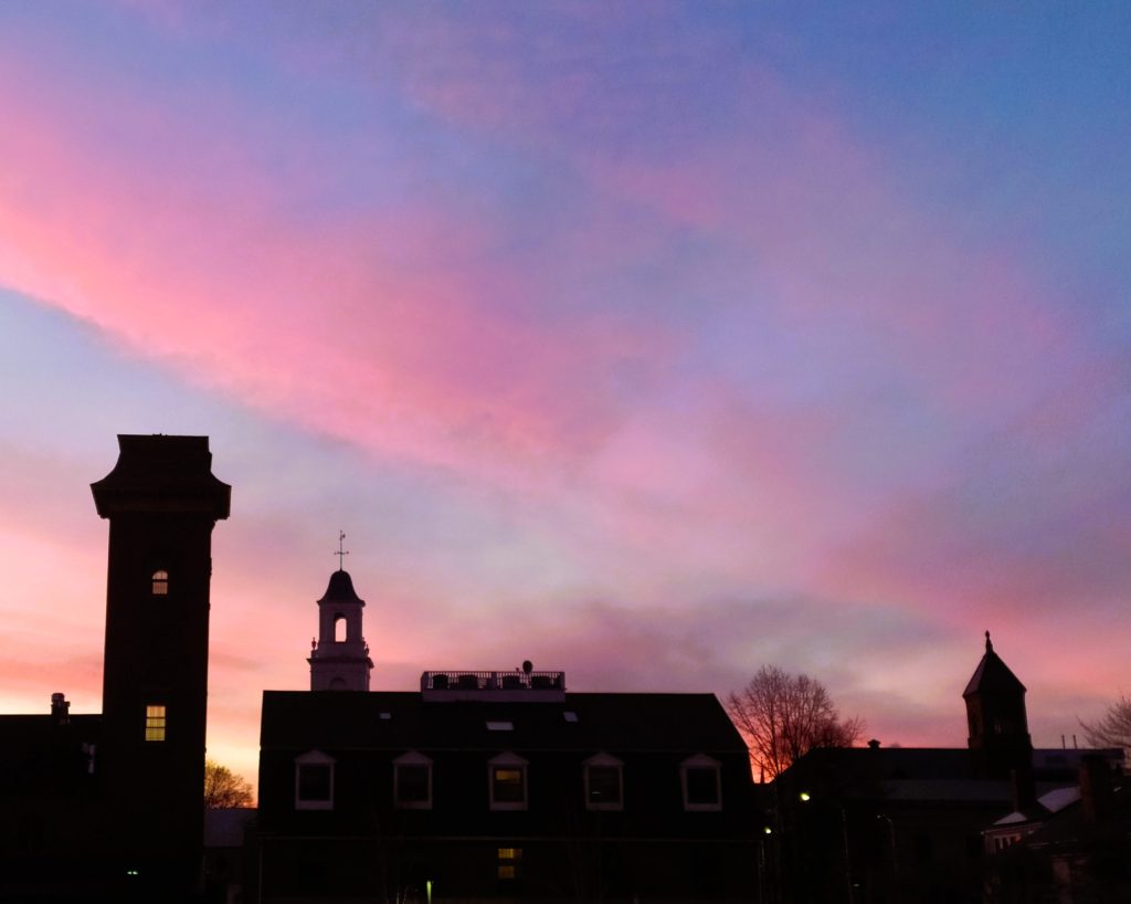 Photo of a pink sunset over a Salem skyline silhouette.